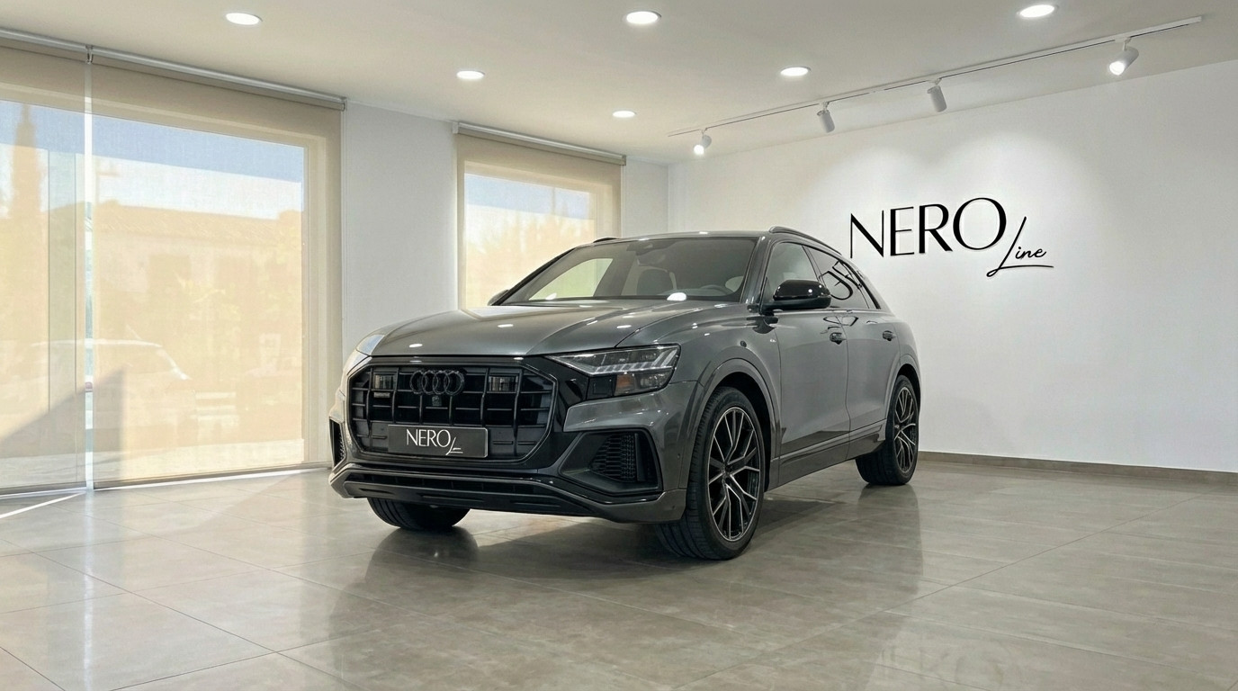 Audi Q8 TDI — Front three-quarter view Alicante The matte gray Audi Q8 TDI is showcased in a showroom, captured from a front three-quarter view in Alicante.
