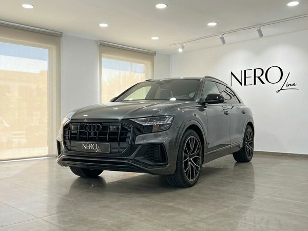 Audi Q8 TDI — Front three-quarter view Alicante The matte gray Audi Q8 TDI is showcased in a showroom, captured from a front three-quarter view in Alicante.