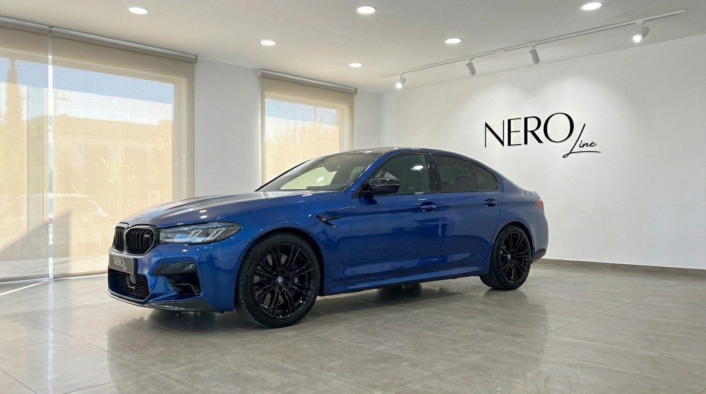 BMW M5 Competition Hybrid — Front-side showroom view A metallic dark blue BMW M5 Competition Hybrid luxury sedan parked in a showroom in Marbella, viewed from the front-side.
