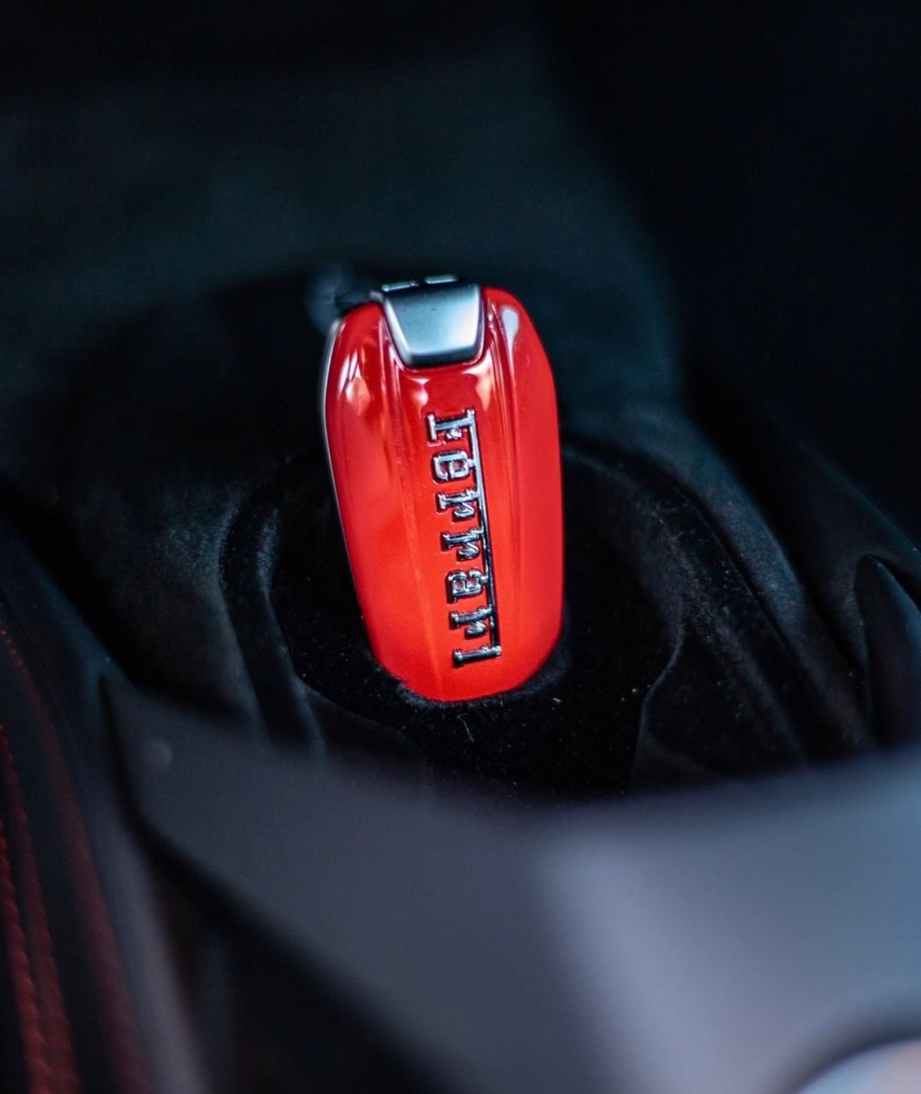 The red Ferrari 488 Spider car key with the brand logo is visible on a dark interior surface in Alicante.