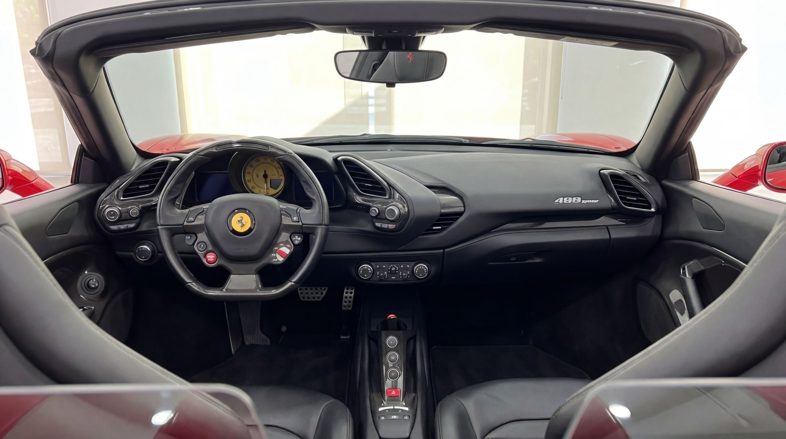 The luxurious cockpit of the Ferrari 488 Spider in racing red, showcasing its steering wheel, dashboard, and central console in Mallorca.