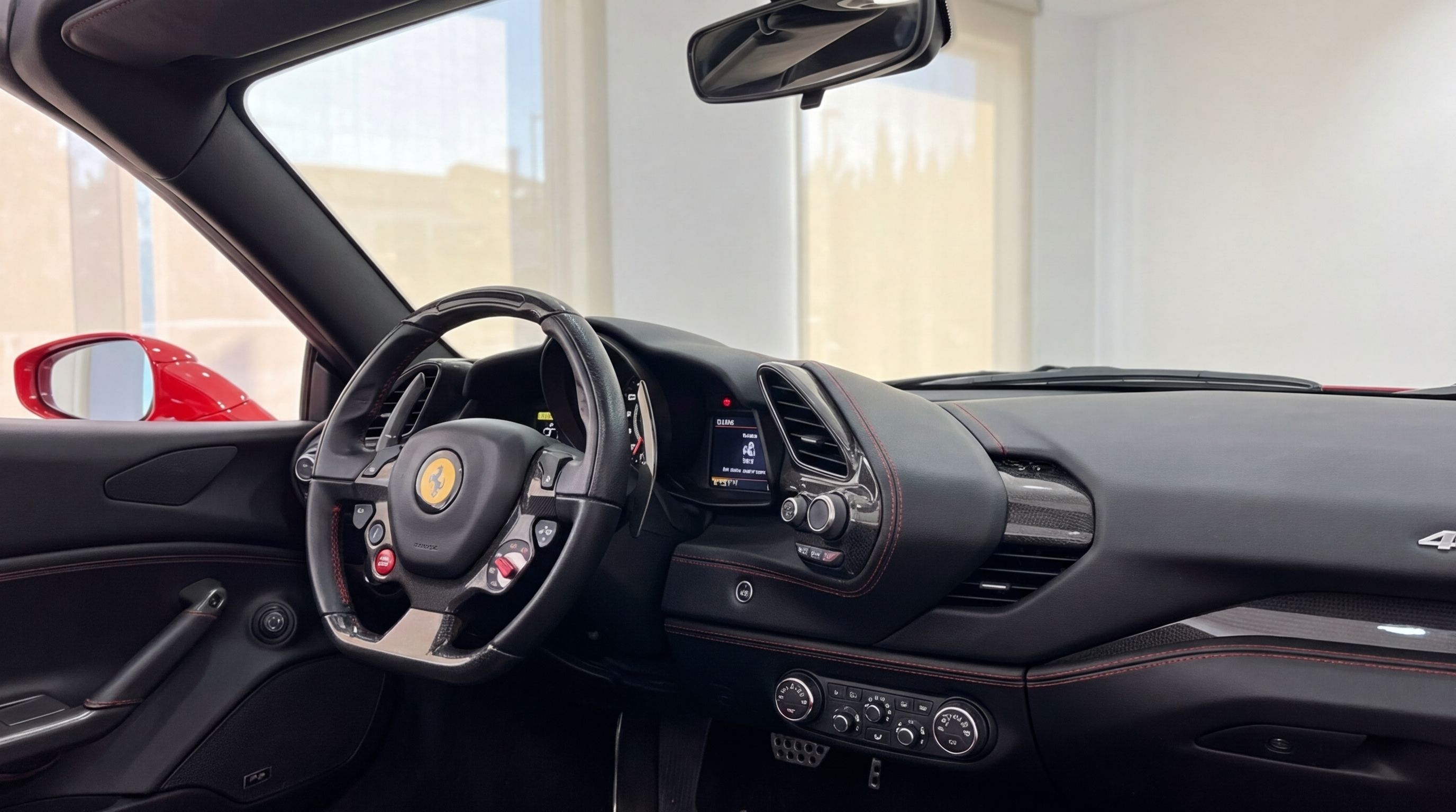 The luxurious interior of the Ferrari 488 Spider in Mallorca, featuring the driver's cockpit with a multifunction steering wheel and red stitching.