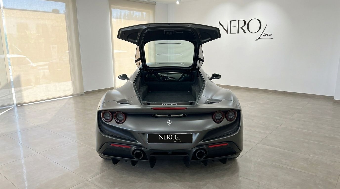 El Ferrari F8 Coupe gris mate se muestra desde la parte trasera en un concesionario de Ibiza, con la cubierta del motor abierta revelando el compartimento de almacenamiento.