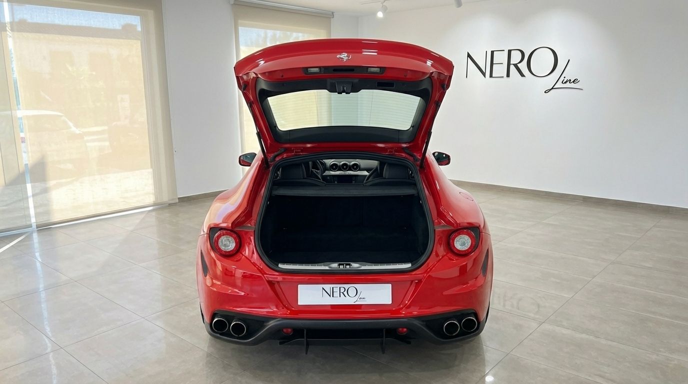 The racing red Ferrari FF is seen from the rear with its trunk open, revealing the spacious cargo area and rear seats in a Valencia showroom.