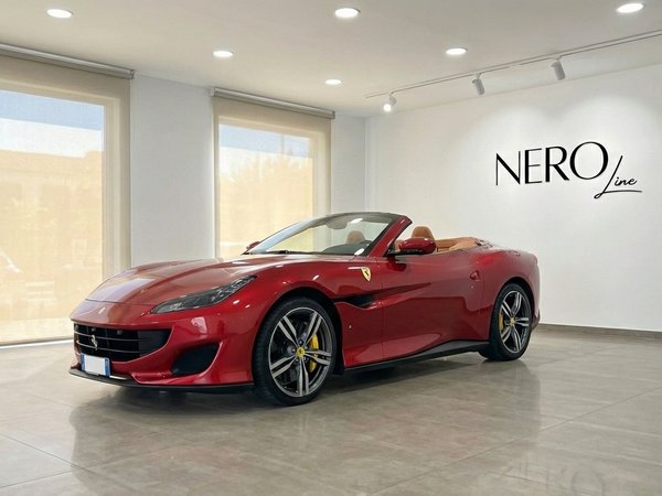 Ferrari Portofino — Convertible in Marbella showroom The burgundy red Ferrari Portofino convertible, with its top down and elegant tan interior, is showcased in a bright Marbella showroom.