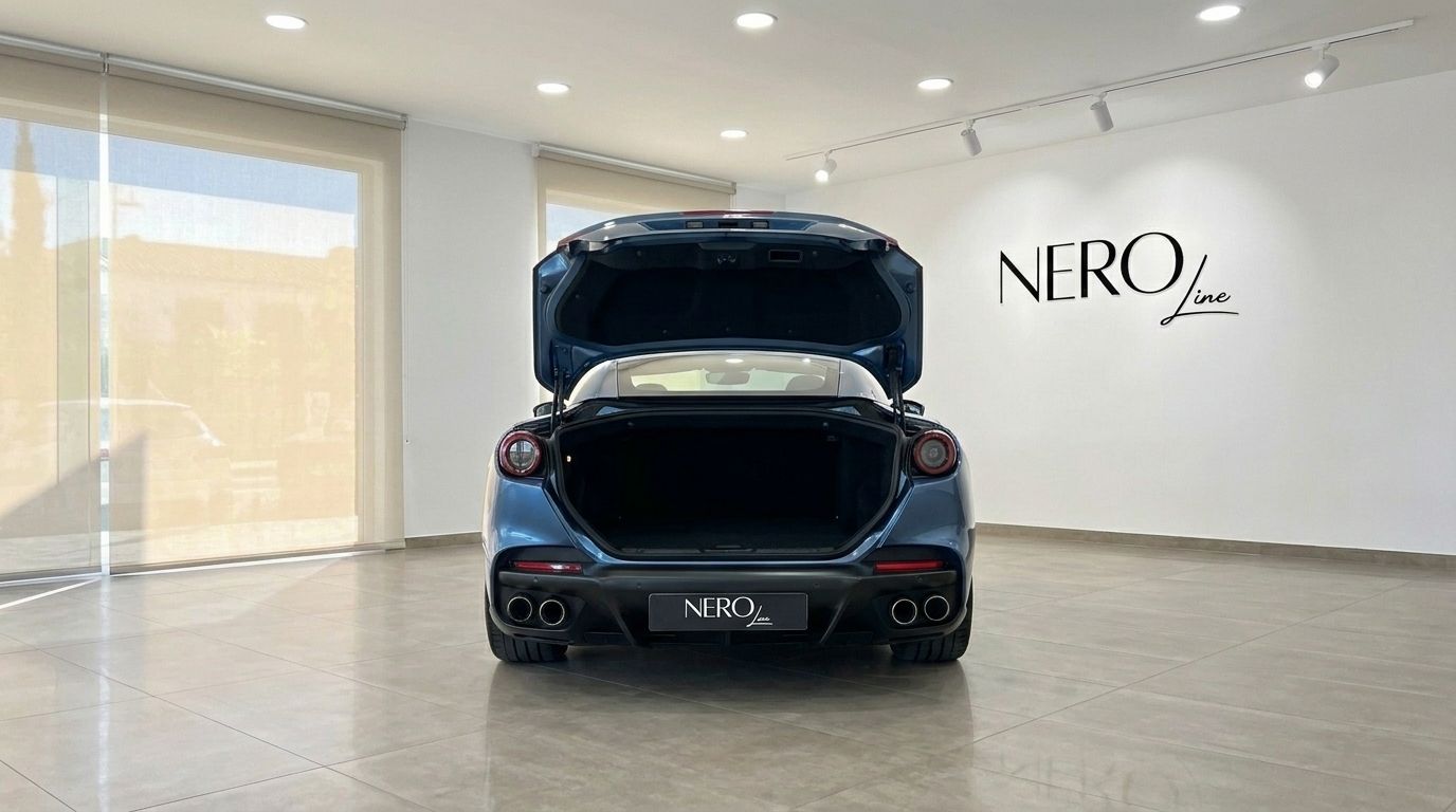 The metallic Blu Roma Ferrari Portofino M is shown from the rear with its trunk open in a showroom in Mallorca.