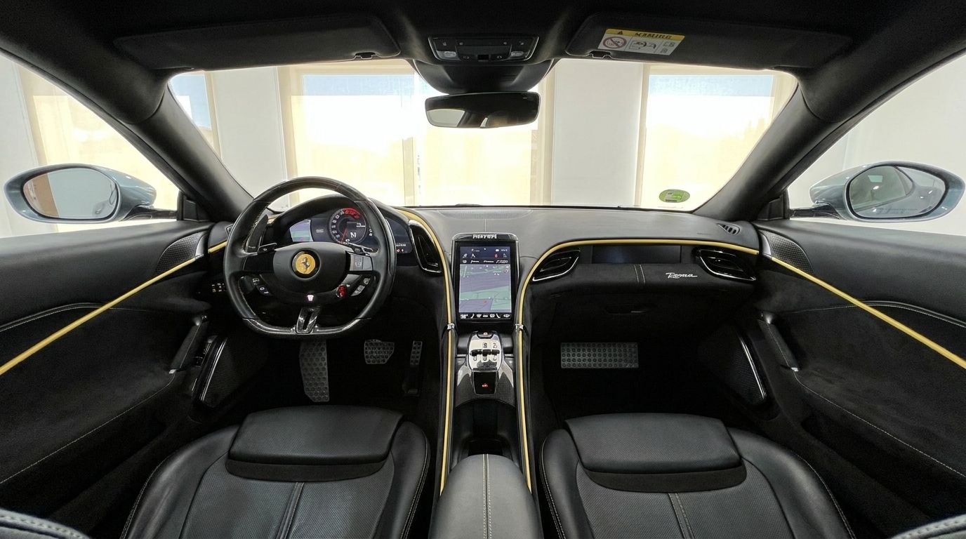 El lujoso interior del Ferrari Roma 2022 en Madrid, mostrando el volante, salpicadero digital, pantalla táctil central y asientos de cuero negro con detalles amarillos.