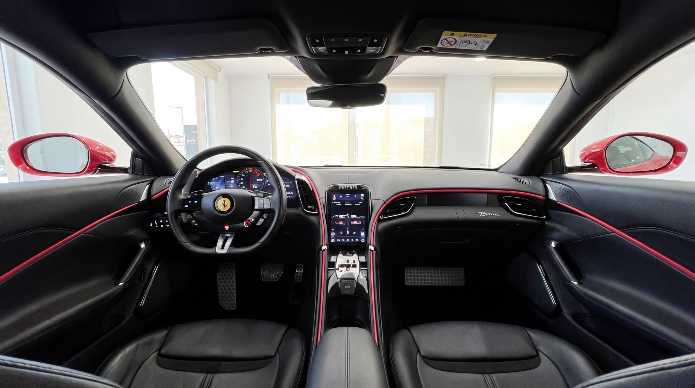 The luxurious interior of the Ferrari Roma in Barcelona, featuring its sleek dashboard, steering wheel, central console, and black leather seats with red accents.