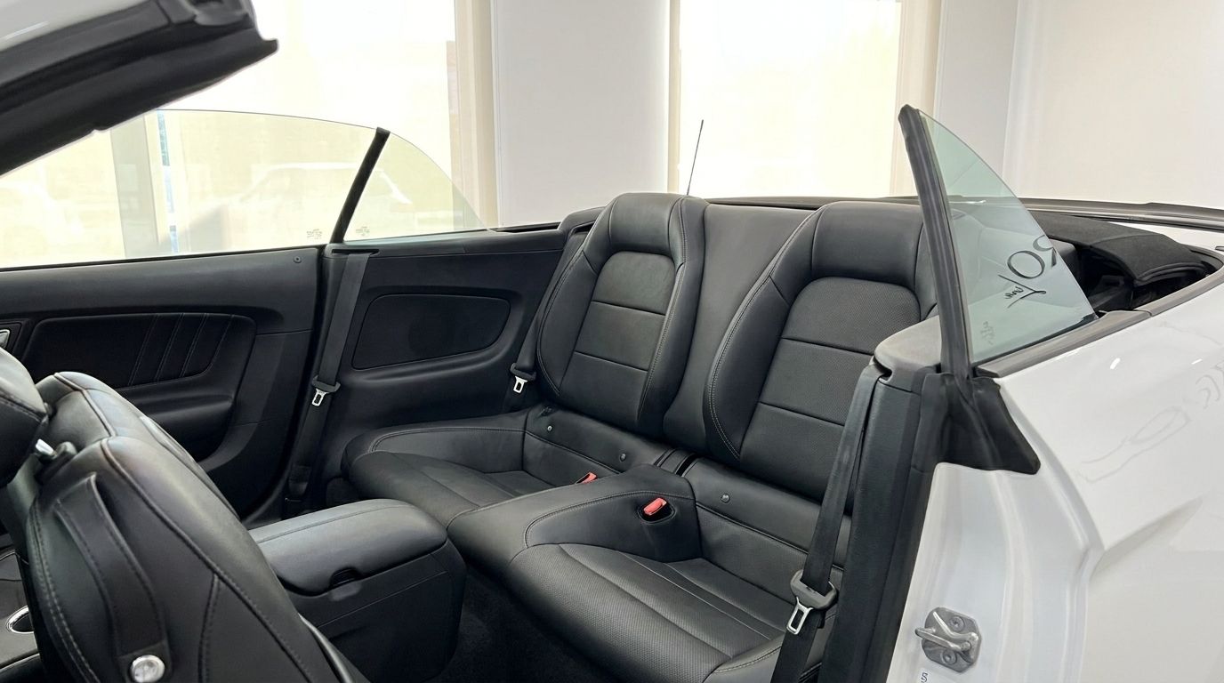 The spacious black leather rear seats of the Ford Mustang 2.3 Convertible with its top down, available in Benidorm.
