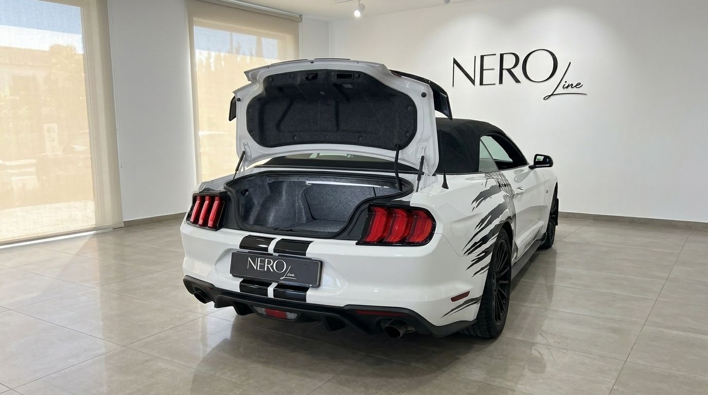 The white Ford Mustang 2.3 Convertible with its trunk open, showcasing the rear design and black stripes in Benidorm.