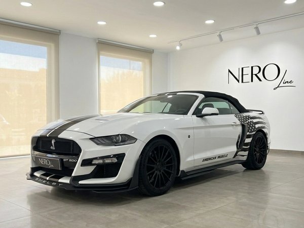 Ford Mustang 2.3 EcoBoost Convertible — Shelby GT500 style in Benidorm White Ford Mustang 2.3 EcoBoost Convertible with black stripes and soft top, Shelby GT500 style, displayed in a Benidorm showroom.