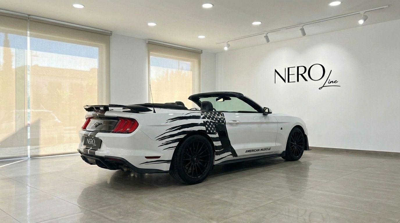 The white Ford Mustang 2.3 EcoBoost Convertible with a black American flag decal is parked in a showroom in Benidorm.