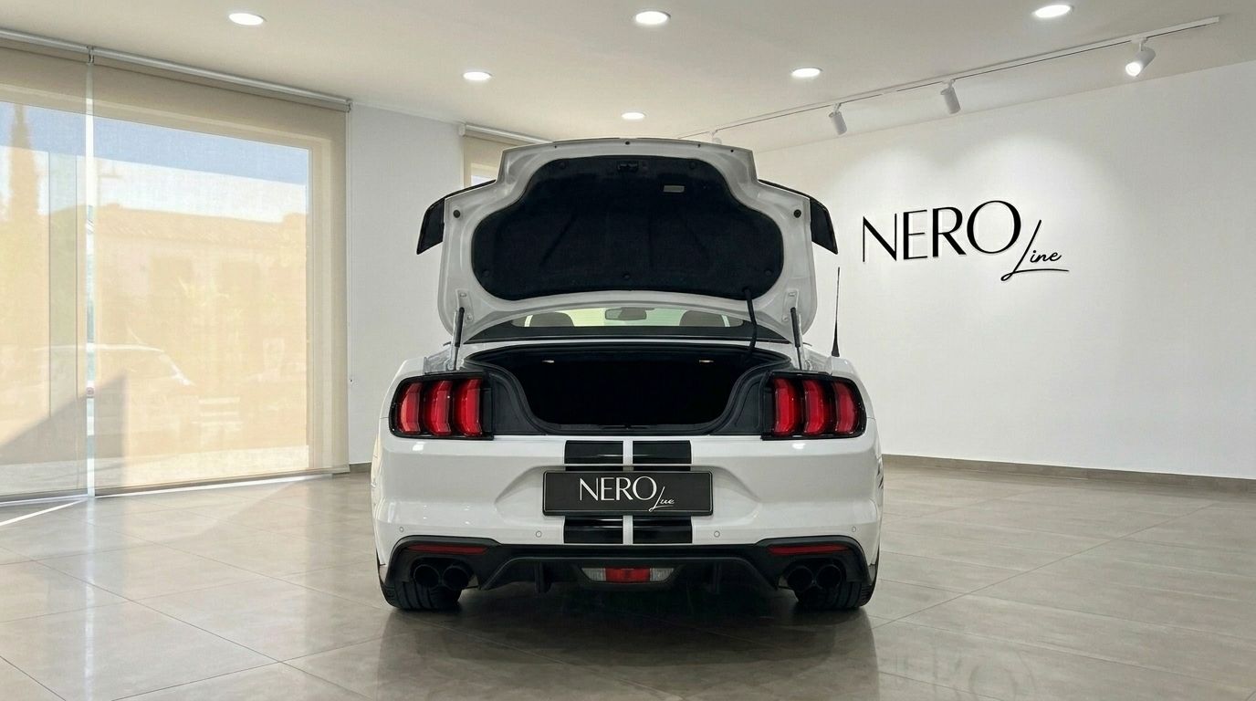 The white Ford Mustang 2.3 EcoBoost Convertible, with its trunk open, is shown from the rear in a showroom in Benidorm.