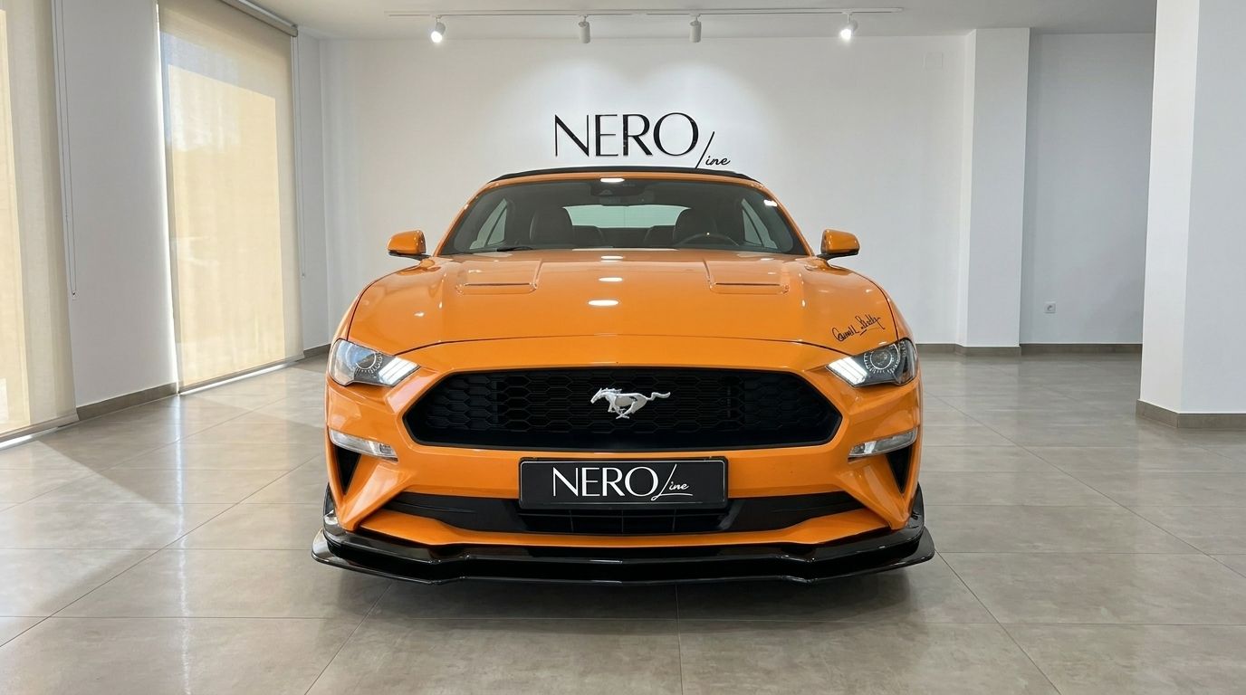 The orange Ford Mustang 2.3 EcoBoost Convertible is shown from the front in a showroom in Alicante.
