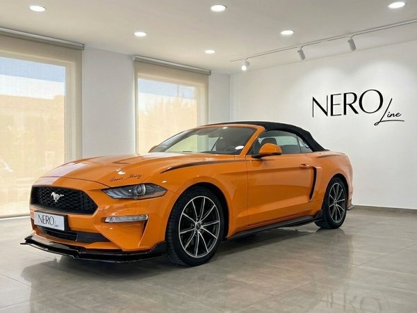 Ford Mustang 2.3 EcoBoost Convertible — Showroom view The orange Ford Mustang 2.3 EcoBoost Convertible is displayed in a showroom, viewed from the front three-quarter angle in Alicante.