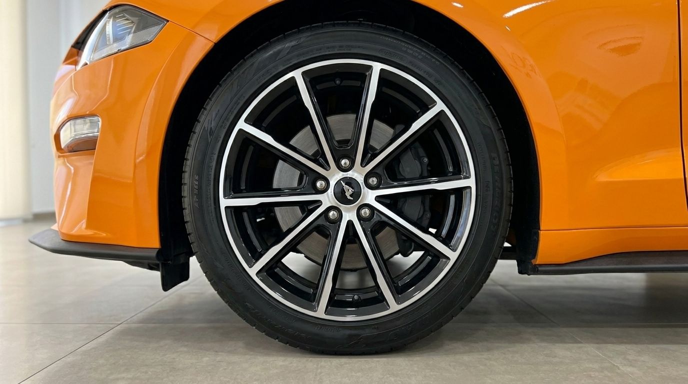 Close-up of the orange Ford Mustang 2.3 EcoBoost Convertible's front wheel and fender in Alicante.