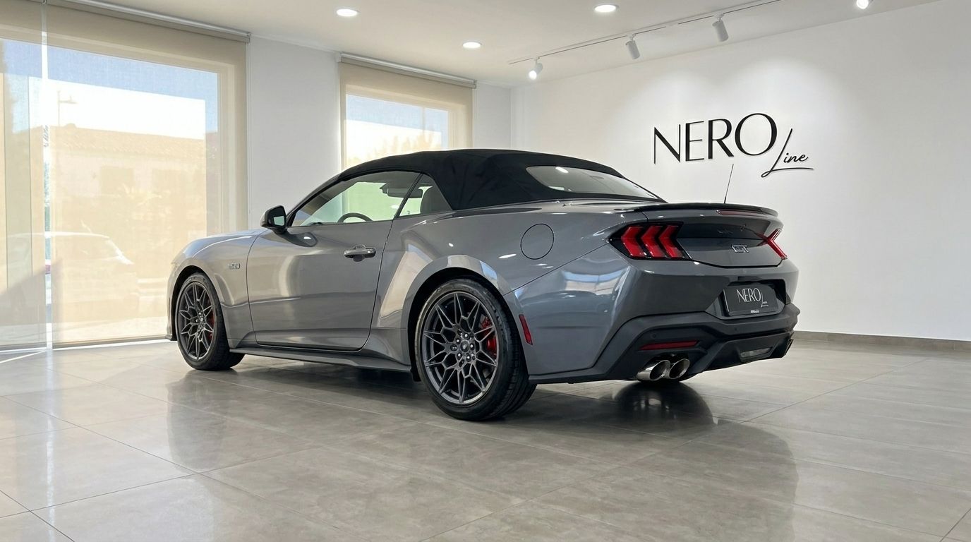La Ford Mustang GT Cabrio (2025) grigio carbonizzato metallizzato è parcheggiata all'interno, vista da tre quarti posteriori con la capote alzata a Madrid.