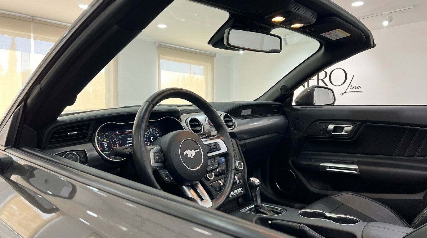 The luxurious black interior of the Ford Mustang GT Convertible in Barcelona, showcasing the steering wheel, dashboard, and gear shifter.