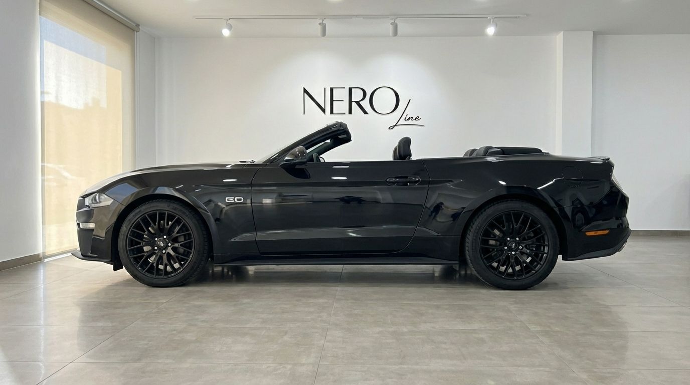 The black Ford Mustang GT Convertible is parked sideways with its top down in a showroom in Barcelona.