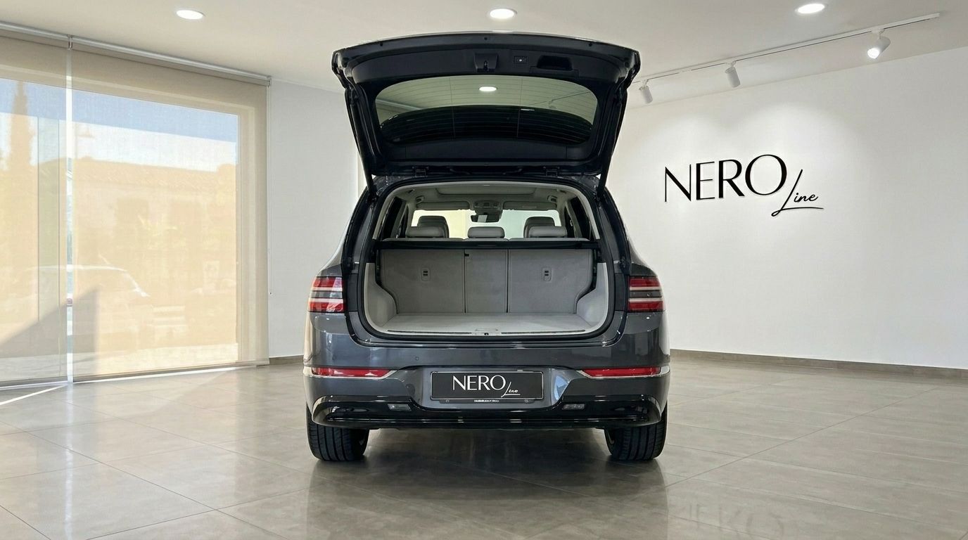 The Genesis GV80's rear view with its tailgate open, showcasing the spacious trunk and rear seats in a bright Alicante showroom.