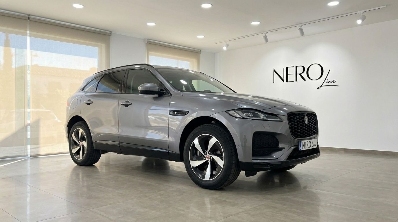 The 2022 Jaguar F-Pace in a sleek gray finish is showcased from a front three-quarter angle in a bright Alicante showroom.