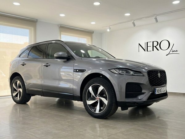 Jaguar F-Pace — Front three-quarter view Alicante The 2022 Jaguar F-Pace in a sleek gray finish is showcased from a front three-quarter angle in a bright Alicante showroom.