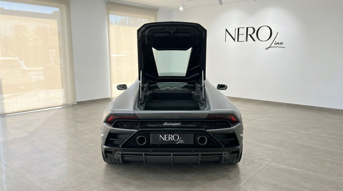 Matte grey Lamborghini Huracan EVO from the rear, with its engine bay open, showcased in a bright showroom in Mallorca.