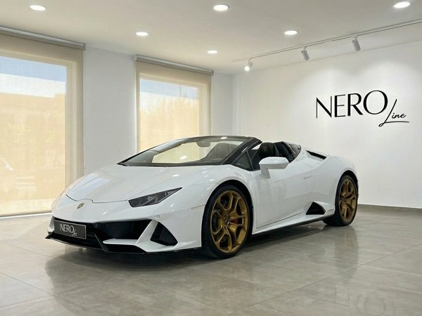Lamborghini Huracan Evo Spyder — Showroom Alicante A white Lamborghini Huracan Evo Spyder with gold wheels is parked in a showroom in Alicante, seen from the front-left angle.