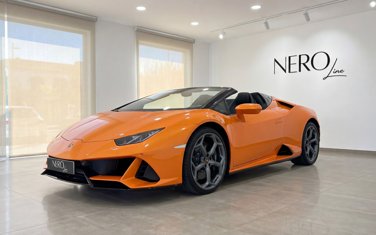 Lamborghini Huracan Evo Spyder — Malaga showroom A vibrant orange Lamborghini Huracan Evo Spyder, convertible top down, is showcased in a modern Malaga showroom.