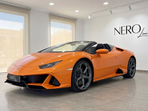 Lamborghini Huracan Evo Spyder — Malaga showroom A vibrant orange Lamborghini Huracan Evo Spyder, convertible top down, is showcased in a modern Malaga showroom.