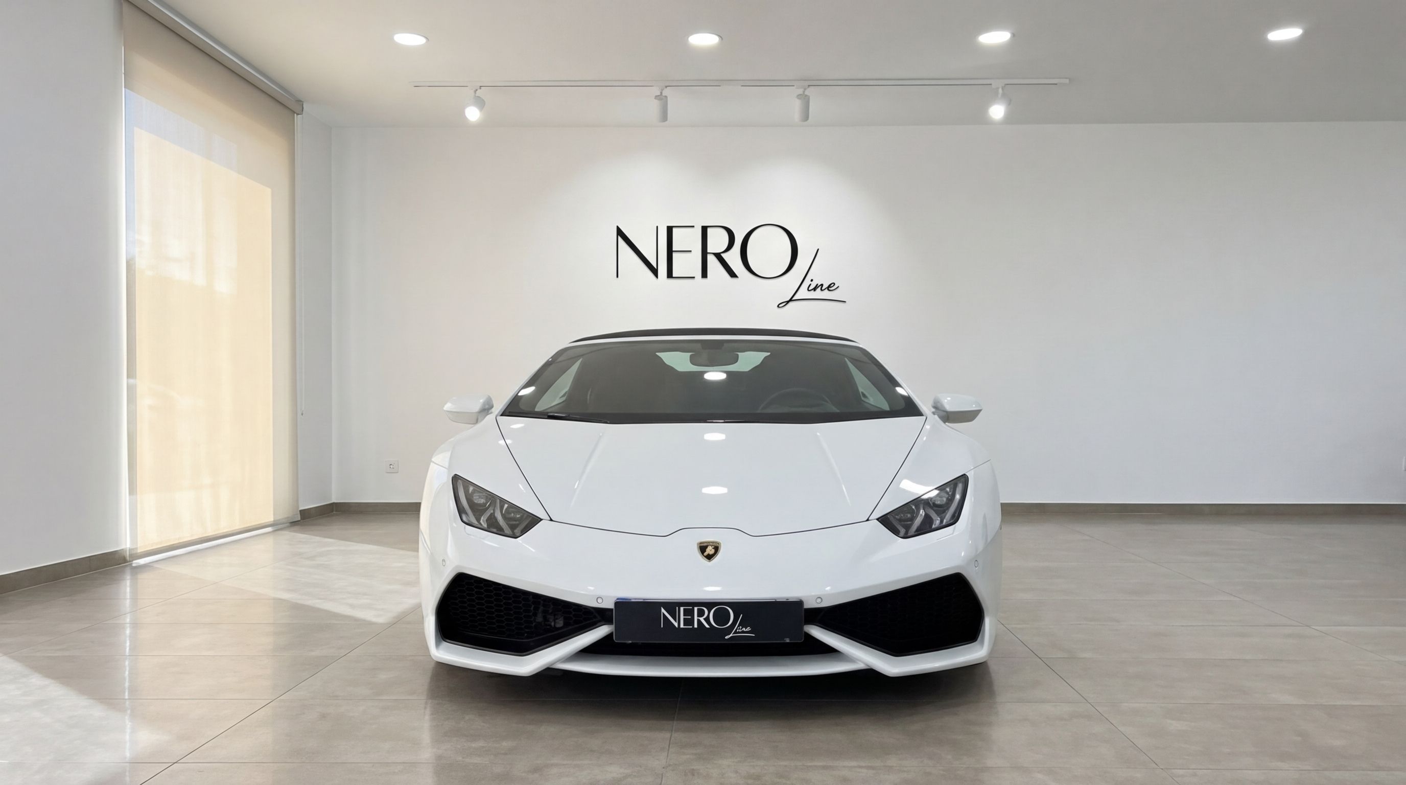 A pristine white Lamborghini Huracan Spyder convertible is showcased from the front view in a bright showroom in Valencia.