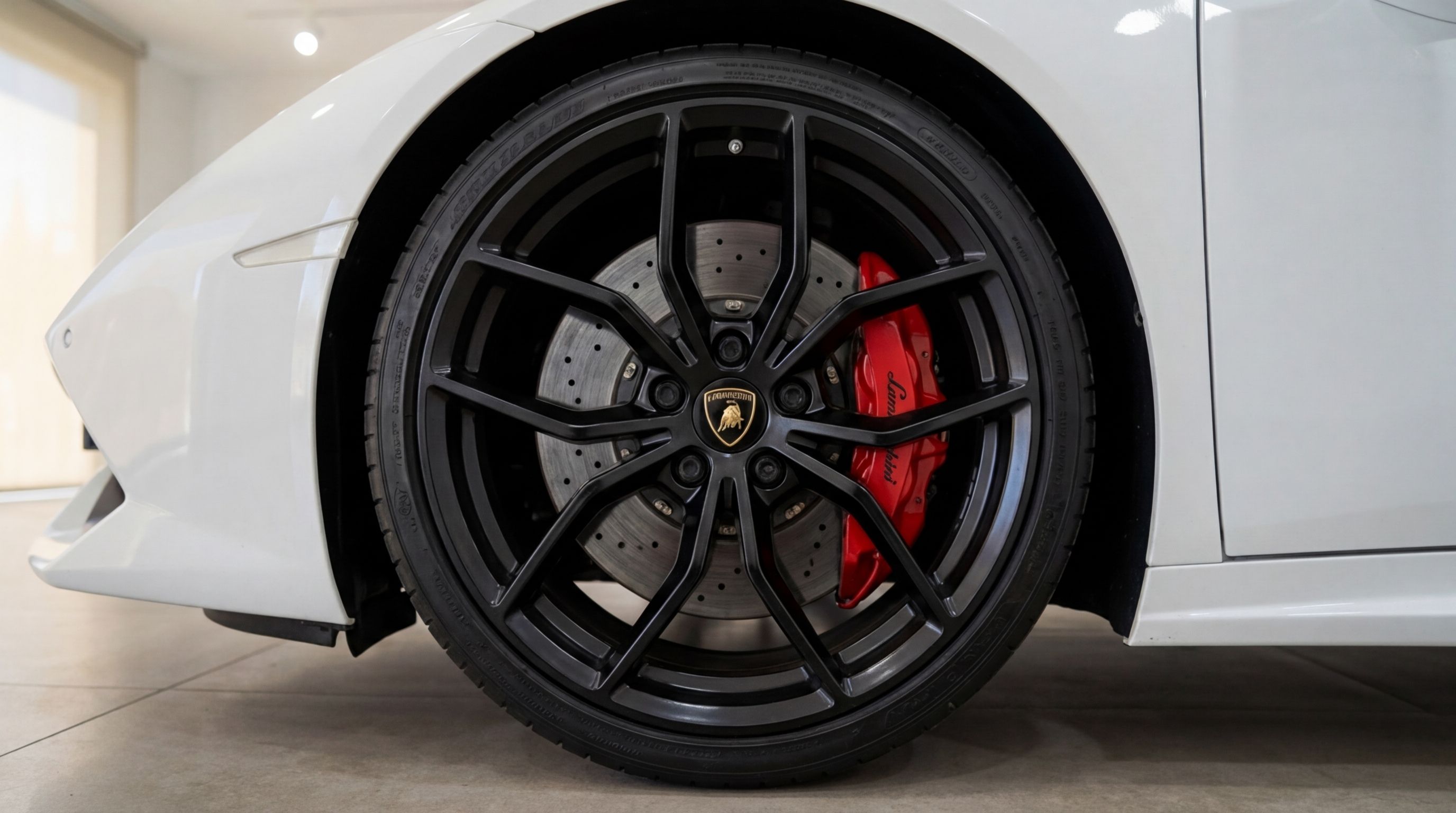 Close-up of the white Lamborghini Huracan Spyder's front wheel, featuring black multi-spoke rims and red brake calipers in Valencia.