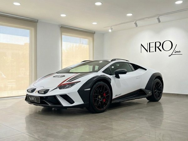 Lamborghini Huracán Sterrato — Concesionario en Madrid Un Lamborghini Huracán Sterrato blanco de 2024 con detalles negros y barras de techo se exhibe en un concesionario en Madrid.