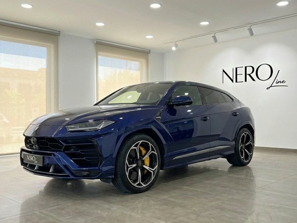 Lamborghini Urus — Azul oscuro en showroom de Madrid El Lamborghini Urus azul oscuro de 2023 se exhibe desde un ángulo frontal tres cuartos en un luminoso showroom en Madrid.