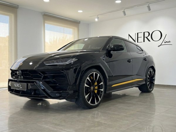 Lamborghini Urus — Front view in Alicante showroom A black Lamborghini Urus with distinctive yellow accents is showcased in a modern showroom in Alicante, front three-quarter view.