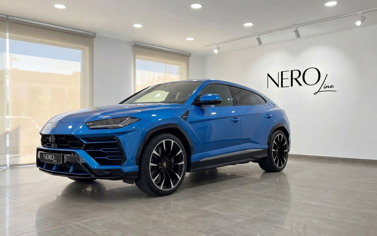 Lamborghini Urus — Metallic Blue SUV in Mallorca A metallic blue Lamborghini Urus is parked indoors, viewed from the front three-quarter angle in Mallorca.