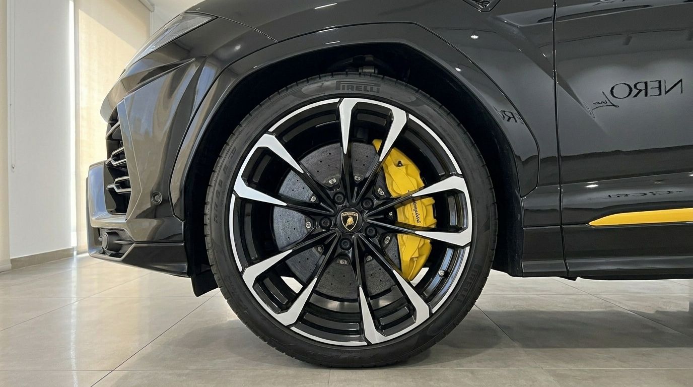 Close-up of the black Lamborghini Urus's front wheel with distinctive black and silver rims and yellow brake calipers in Alicante.
