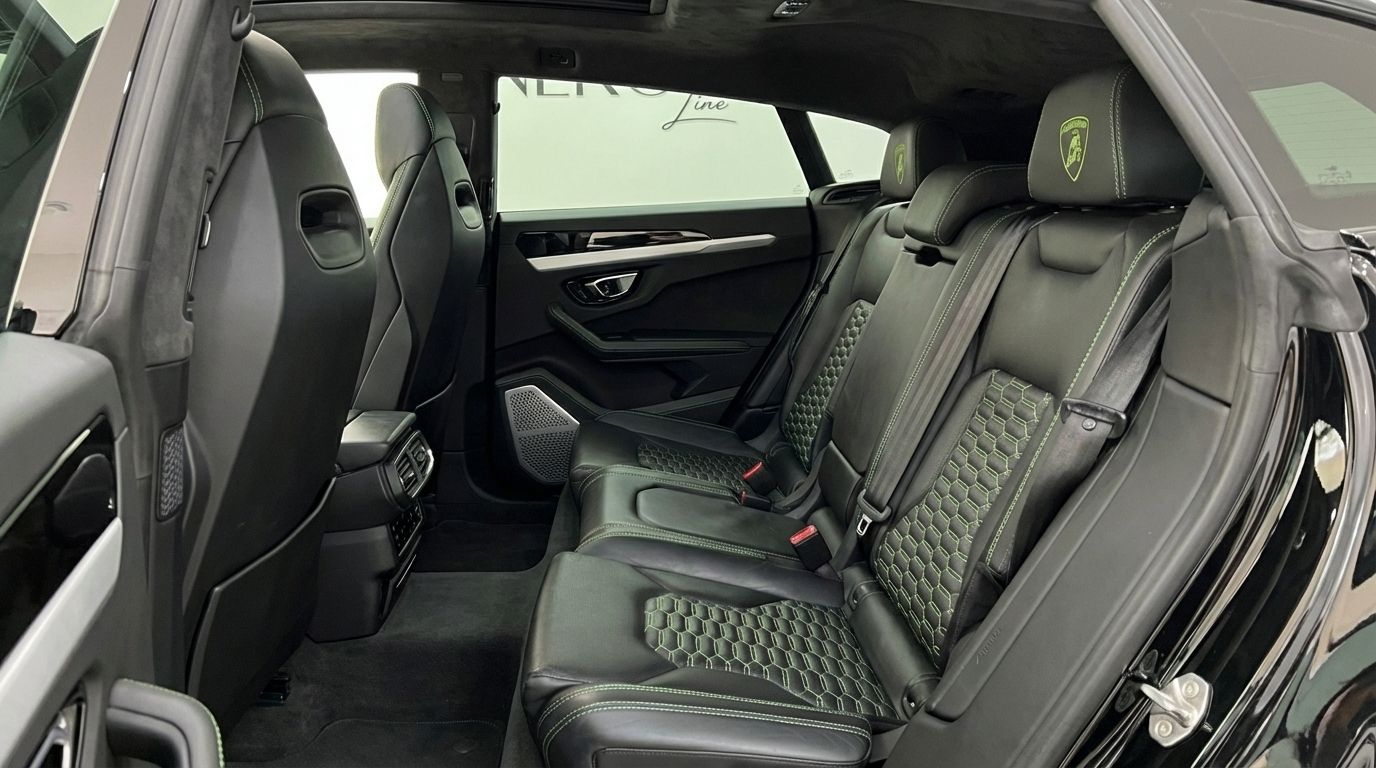 The luxurious black leather rear seats with distinctive green hexagonal stitching and Lamborghini logo headrests inside the Lamborghini Urus in Barcelona.