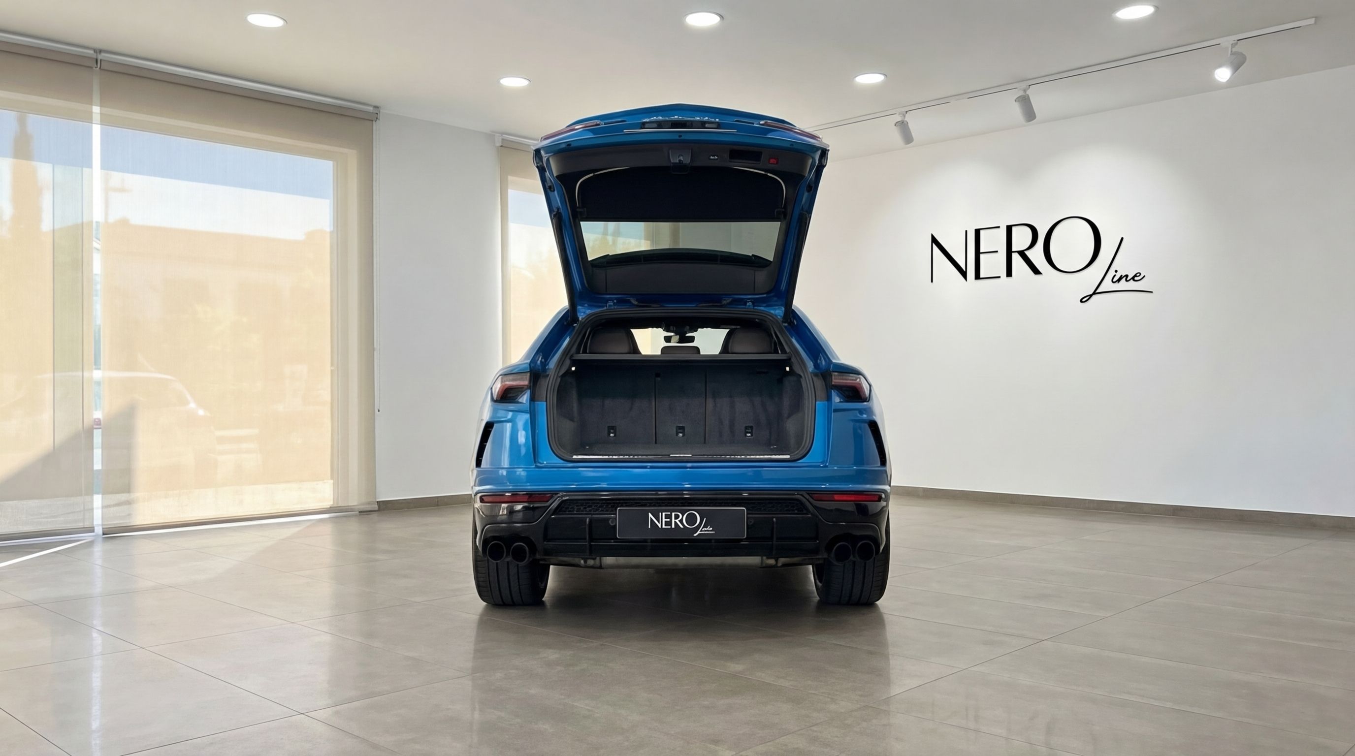 Metallic blue Lamborghini Urus shown from the rear with its trunk open, displayed in a showroom in Mallorca.
