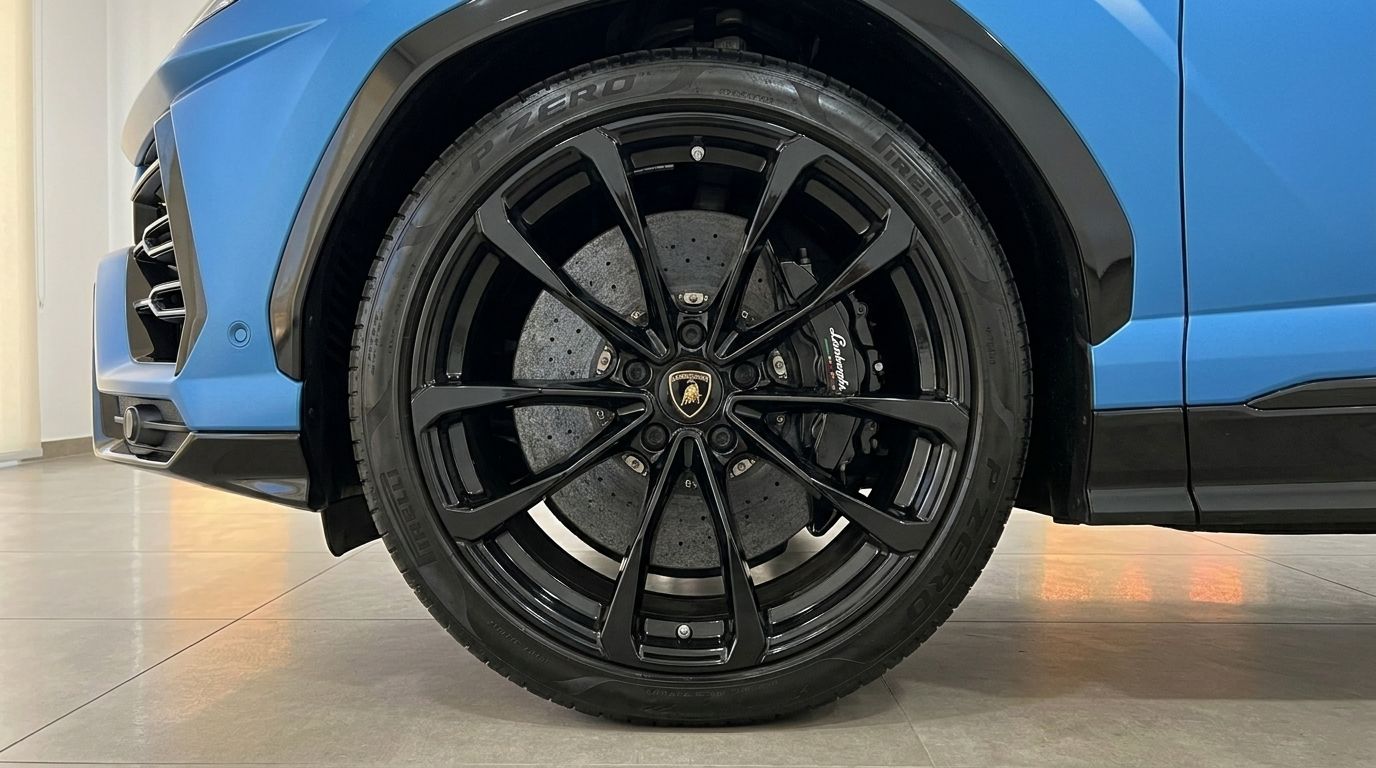 Una vista de cerca de la rueda delantera del Lamborghini Urus S con llanta negra multirradio y frenos cerámicos de carbono en Madrid.