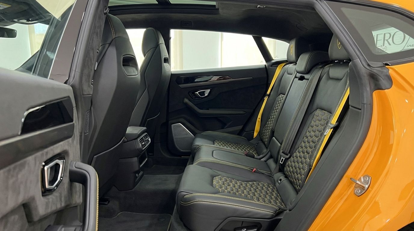 The luxurious rear interior of the Lamborghini Urus S in Barcelona, featuring black leather seats with yellow honeycomb stitching and matching seatbelts.