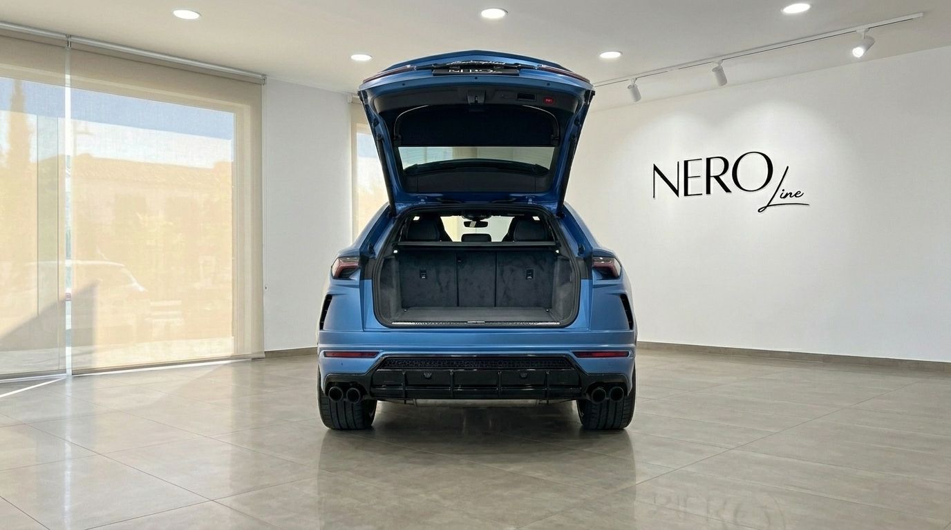 El Lamborghini Urus S azul se muestra desde la parte trasera con el maletero abierto, revelando su espaciosa área de carga en un concesionario de Madrid.