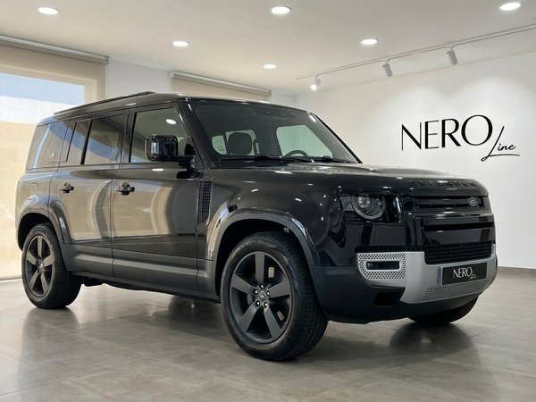 Land Rover Defender — Luxury SUV rental in Madrid A sleek gloss Santorini Black Land Rover Defender 2025 is showcased in a modern Madrid showroom, viewed from the front three-quarter angle.