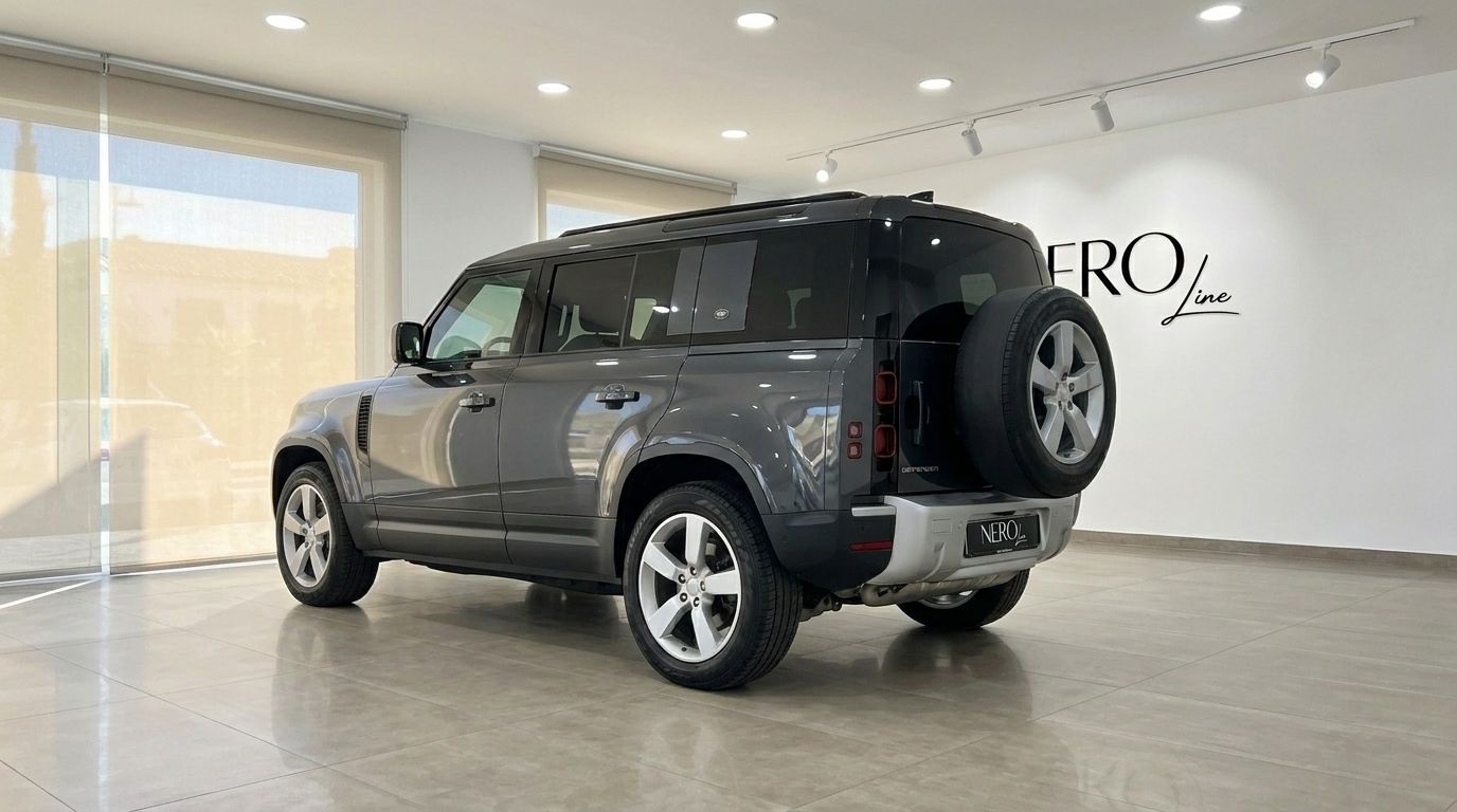 The gloss dark grey metallic Land Rover Defender 3.0 is showcased from a rear three-quarter view in a Marbella showroom.