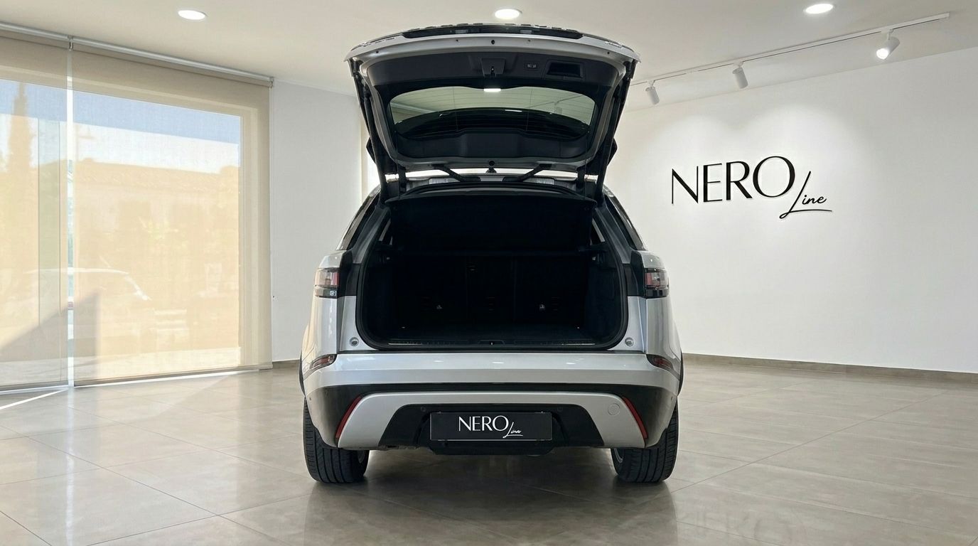 The rear view of a silver Land Rover Range Rover Velar with its trunk open, showcasing ample storage space in Alicante.