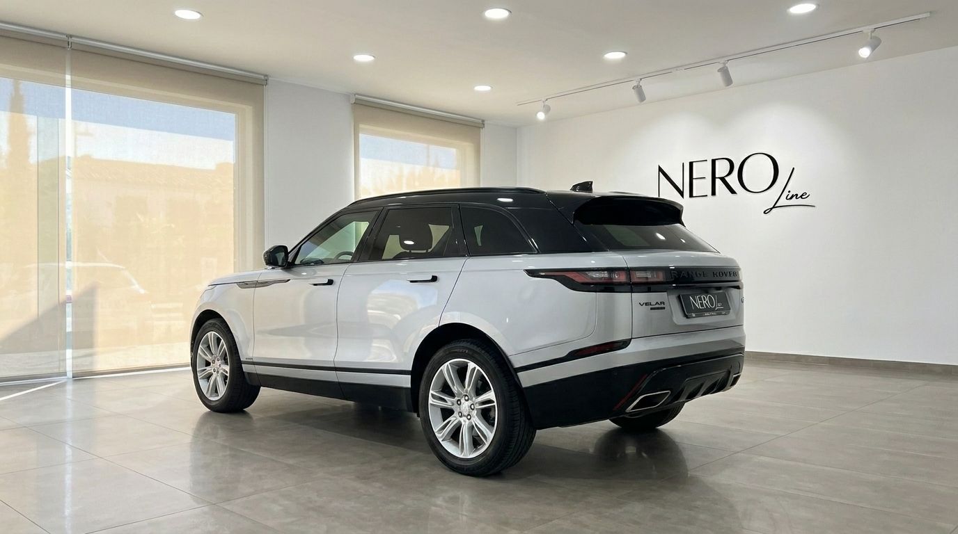 A silver Land Rover Range Rover Velar is parked in a showroom, captured from its rear three-quarter angle in Alicante.