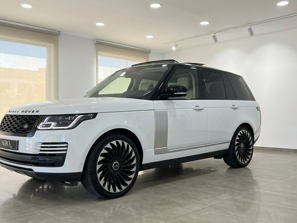 Land Rover Range Rover Vogue — Front view Alicante The white 2021 Land Rover Range Rover Vogue is showcased from a front three-quarter angle in a showroom in Alicante.