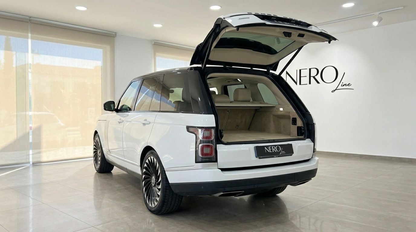 The white Land Rover Range Rover Vogue in Alicante is shown from the rear with its spacious boot open inside a showroom.