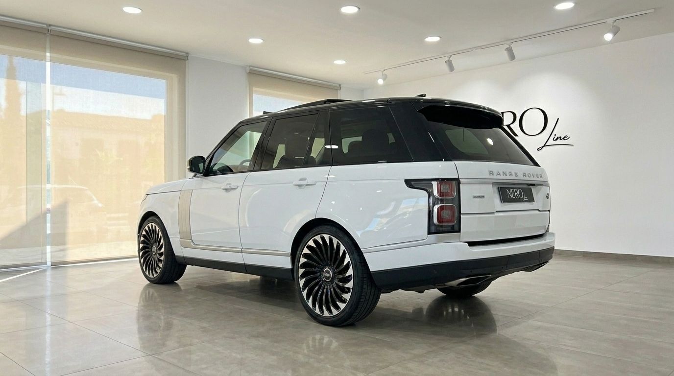 A white Land Rover Range Rover Vogue 2021 is showcased from a rear three-quarter angle in a modern showroom in Alicante.