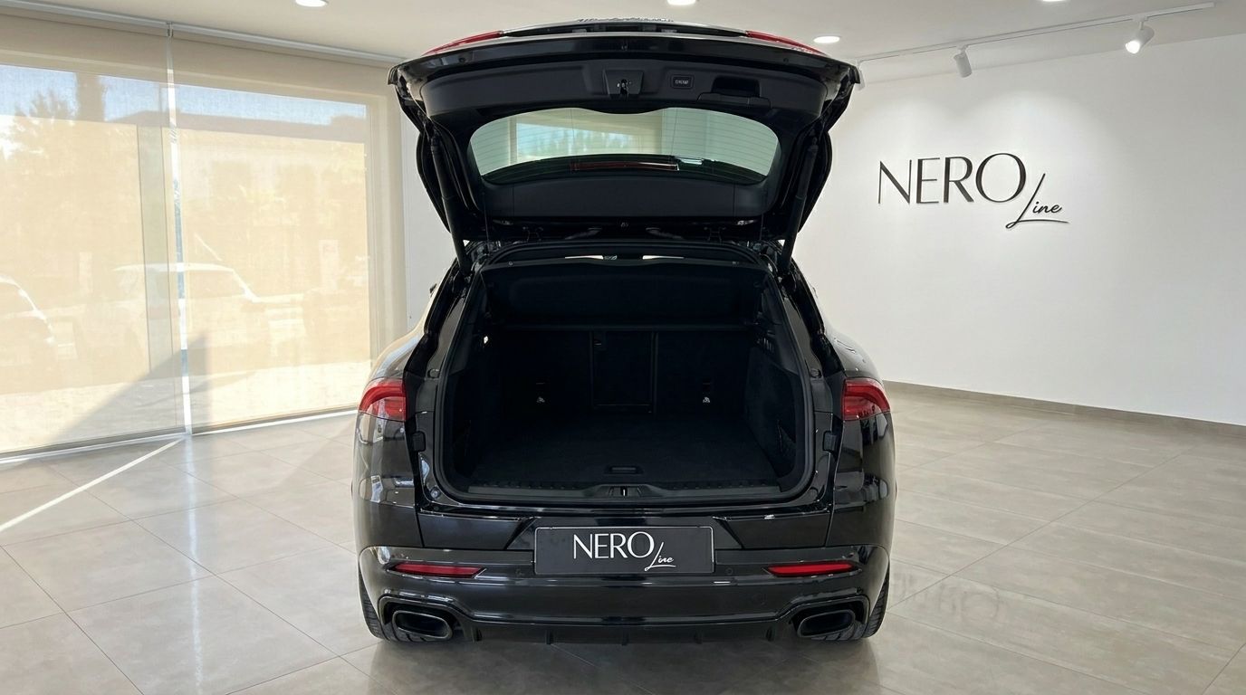 The rear view of the black 2024 Maserati Grecale with its trunk open, showcasing ample cargo space in a Marbella showroom.